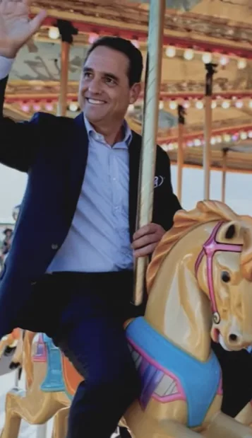 AI film still: a smiling man in a suit waving from a carousel horse