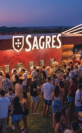 AI visualisation of a Sagres beer brand activation at an outdoor event at dusk, with a crowd in front of the bar